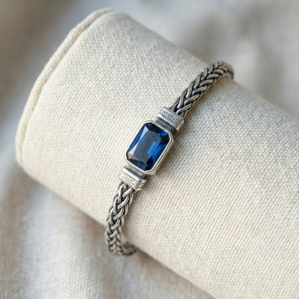 Silver bracelet with a blue gemstone on a beige fabric background