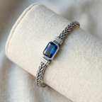 Silver bracelet with a blue gemstone on a beige fabric background