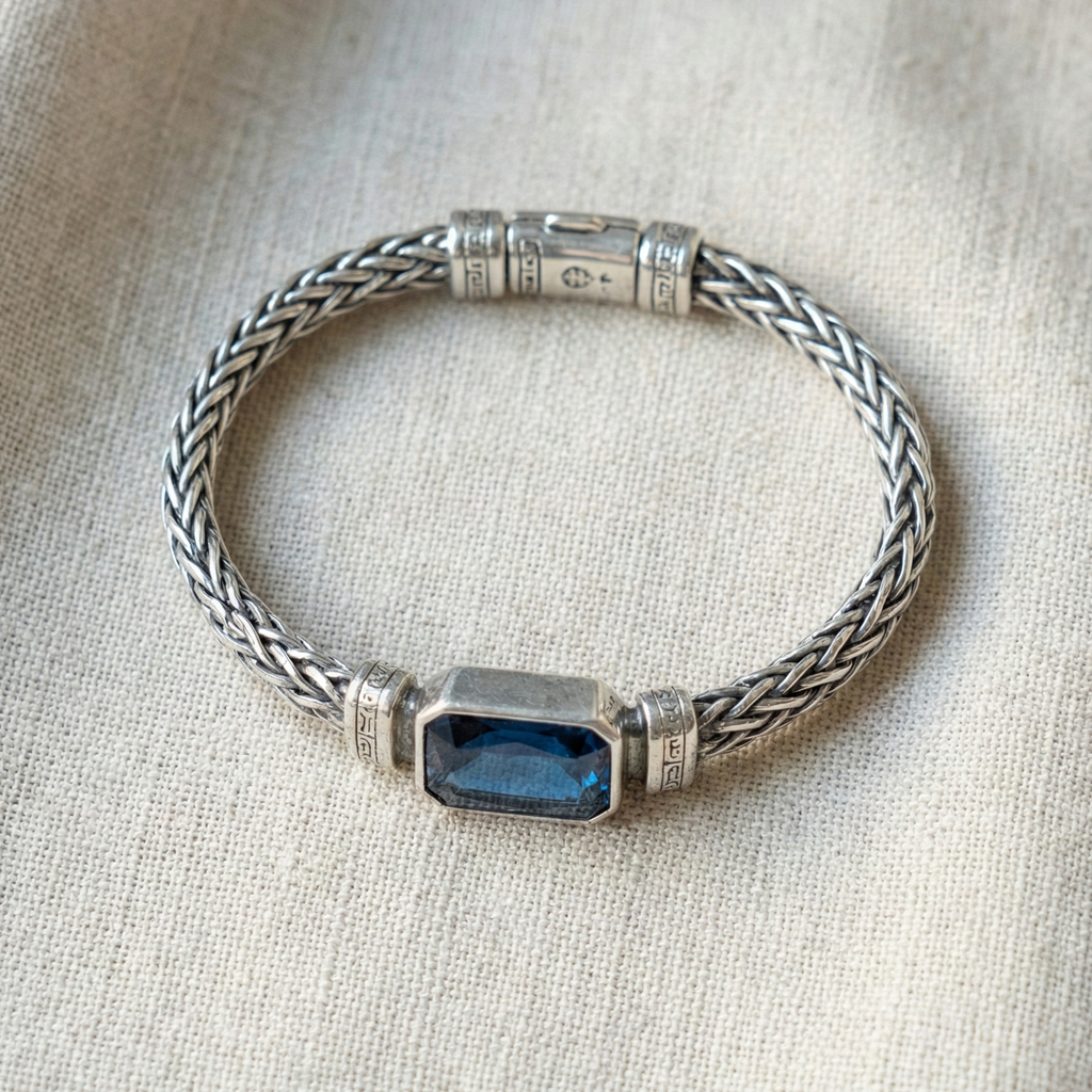 Silver bracelet with a blue gemstone on a beige fabric background