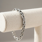Silver chain bracelet on a beige jewelry stand with a neutral background