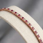 Jewelry bracelet with red and white gemstones on a beige cushion against a gray background