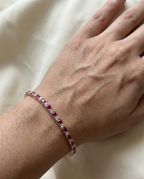 Bracelet with red gemstones on a wrist against a light background