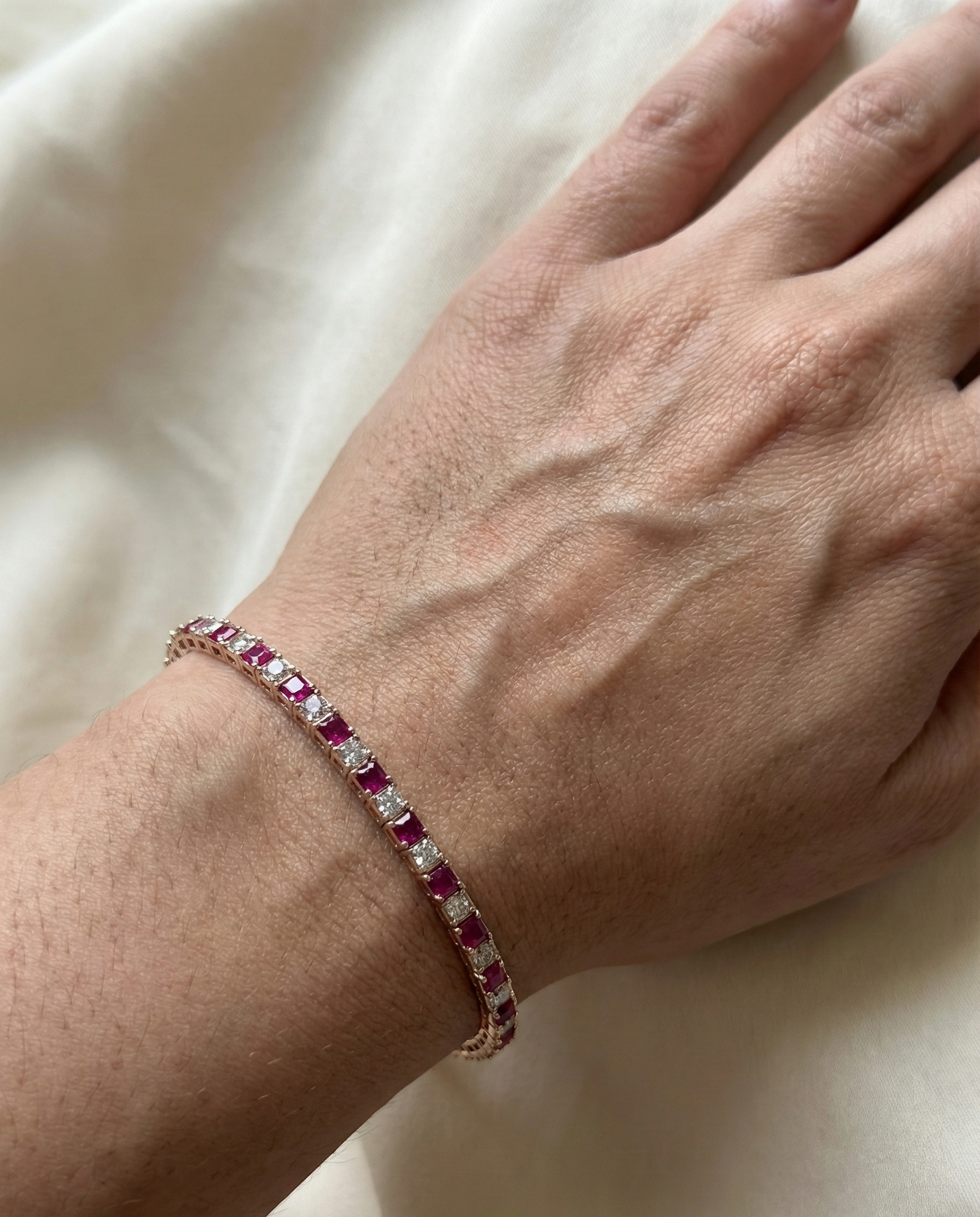 Bracelet with red gemstones on a wrist against a light background
