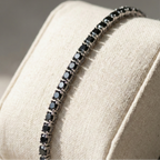 Black beaded bracelet on a beige cushion with a blurred background