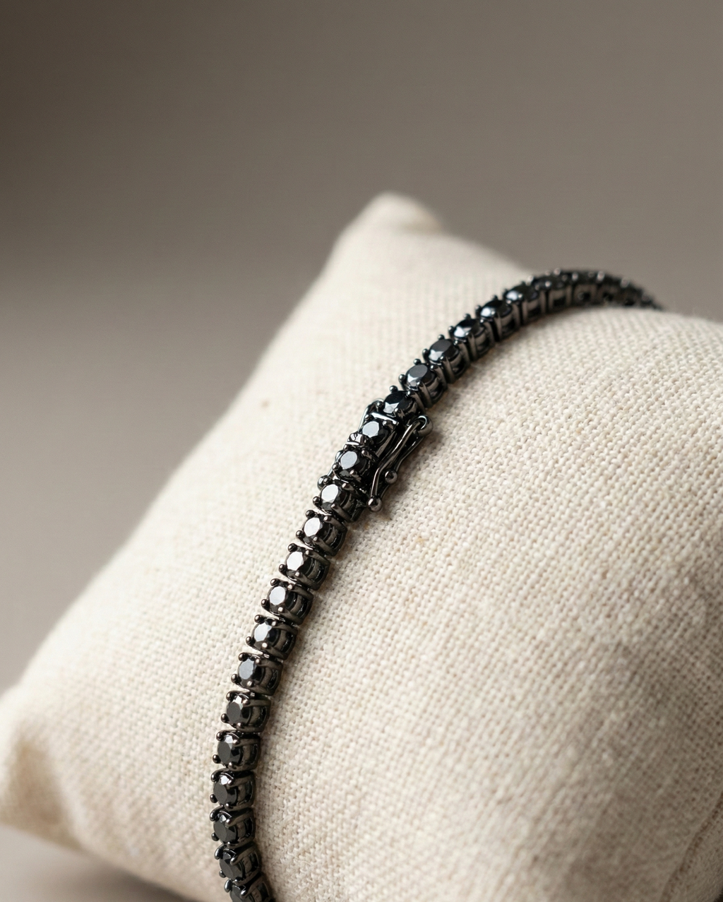 Black beaded bracelet on a beige cushion with a neutral background