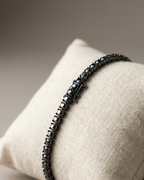 Black beaded bracelet on a beige cushion with a neutral background